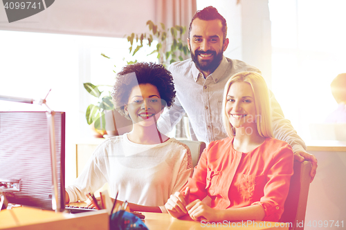 Image of happy creative team with computer in office