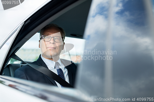 Image of senior businessman driving on car back seat