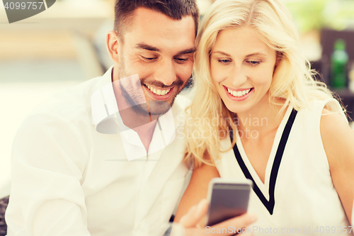 Image of happy couple with smartphone at city street cafe