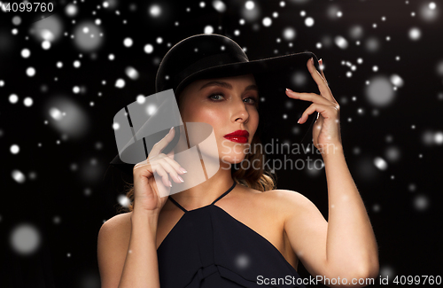 Image of beautiful woman in black hat over snow