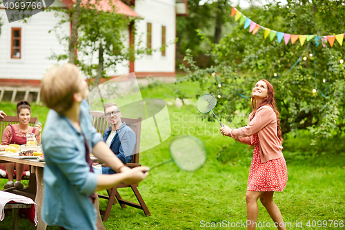 Image of happy friends playing badminton at summer garden