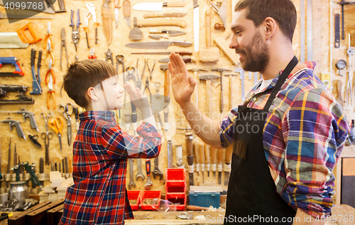 Image of father and little son making high five at workshop