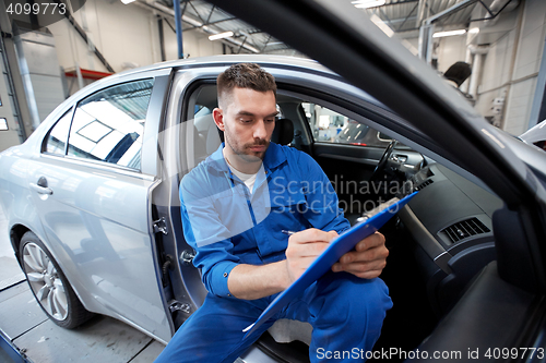 Image of auto mechanic man with clipboard at car workshop