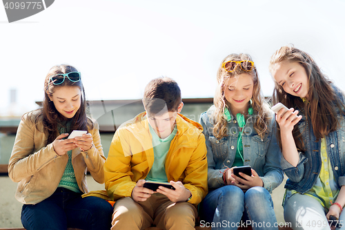 Image of happy teenage friends with smartphones outdoors