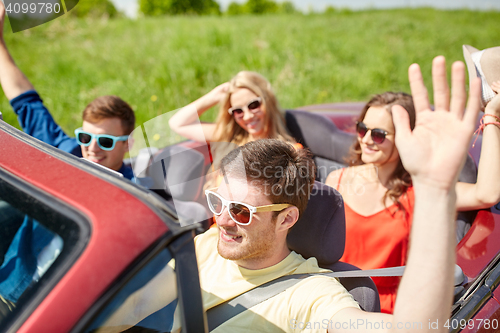 Image of happy friends driving in cabriolet car at country