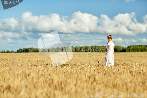 Image of happy young woman in flower wreath on cereal field