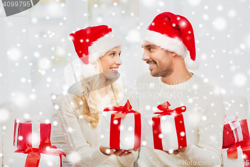 Image of happy couple at home exchanging christmas gifts