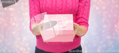 Image of close up of woman in pink sweater holding gift box