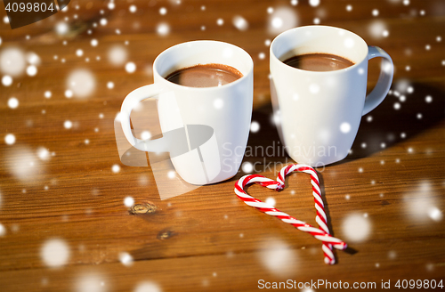 Image of christmas candy canes and cups on wooden table