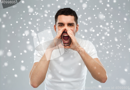 Image of angry shouting man in t-shirt over snow background