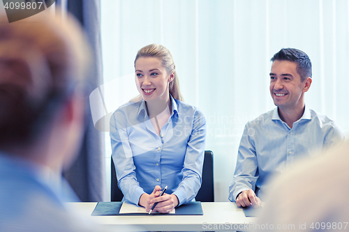 Image of group of smiling businesspeople meeting in office