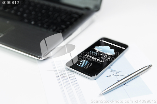 Image of close up of smartphone with weather cast on screen