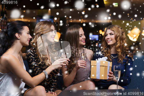 Image of happy women with champagne and gift at night club