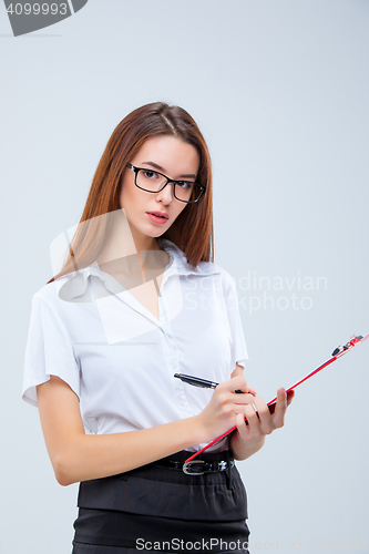 Image of The young business woman with pen and tablet for notes on gray background