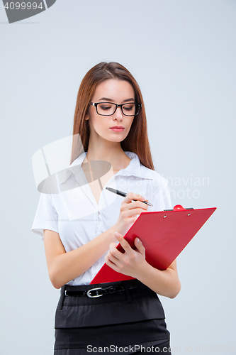 Image of The young business woman with pen and tablet for notes on gray background