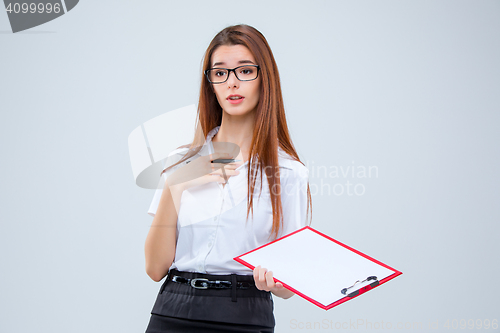Image of The young business woman with pen and tablet for notes on gray background