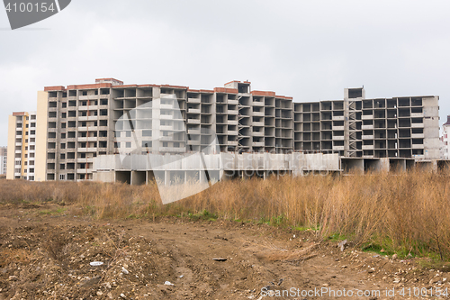 Image of Abandoned construction of multi-storey residential complex, overgrown with weeds