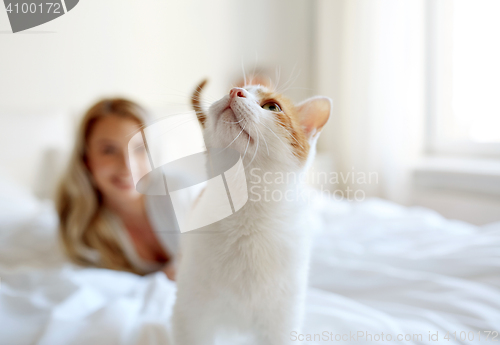 Image of happy young woman with cat in bed at home