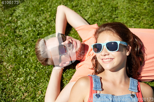 Image of happy teenage couple lying on grass at summer