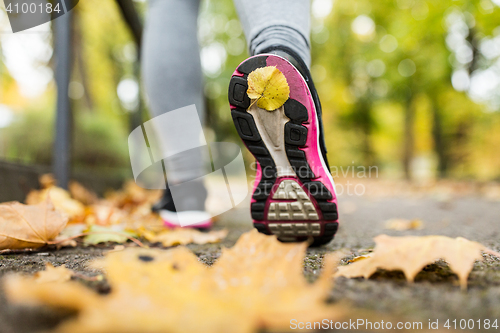 Image of close up of young woman running in autumn park