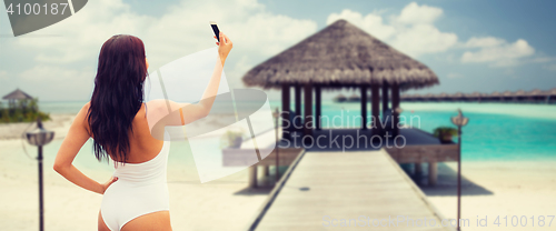 Image of young woman taking selfie with smartphone