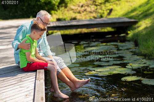 Image of grandfather and grandson sitting on river berth