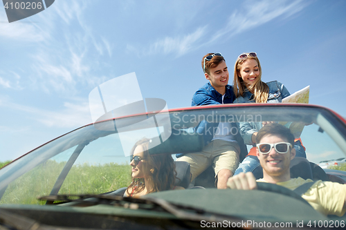 Image of happy friends with map driving in cabriolet car