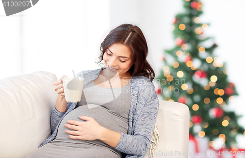 Image of happy pregnant woman with cup drinking tea at home