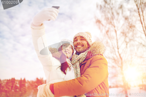 Image of happy couple taking selfie by smartphone in winter