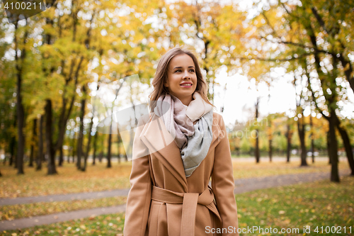 Image of beautiful happy young woman walking in autumn park