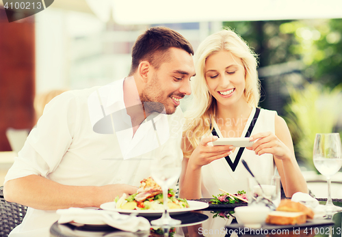 Image of happy couple with smatphone photographing food