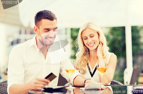 Image of happy couple with bank card and bill at restaurant