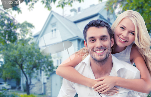 Image of smiling couple hugging over house background