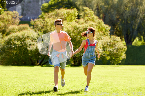 Image of happy teenage couple running at summer park