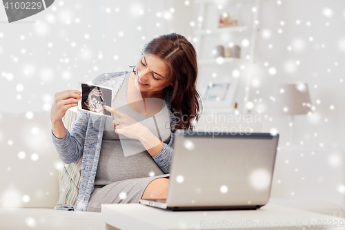 Image of happy pregnant woman with ultrasound image at home