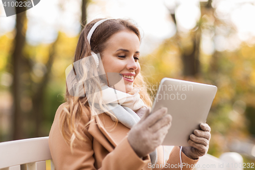 Image of woman with tablet pc and headphones in autumn park