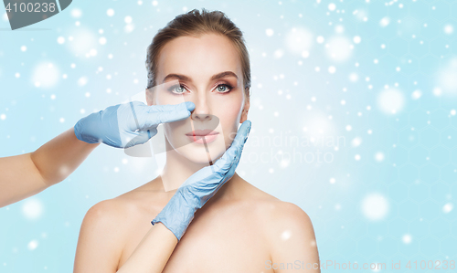 Image of surgeon or beautician hands touching woman face