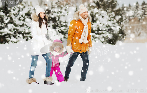 Image of happy family in winter clothes walking outdoors