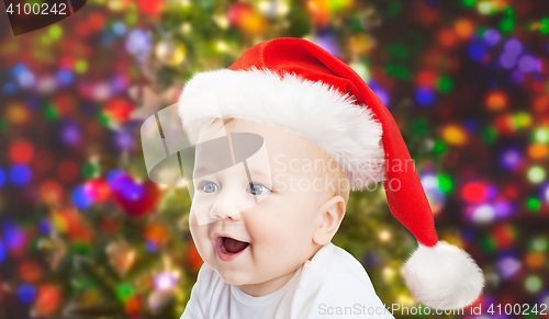 Image of baby boy in christmas santa hat over blue lights