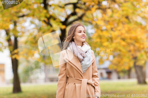 Image of beautiful happy young woman walking in autumn park
