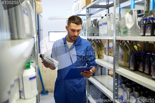 Image of auto mechanic with oil and clipboard at car shop