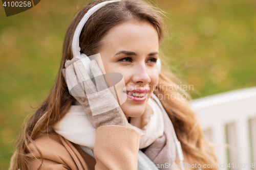 Image of happy woman with headphones in autumn park