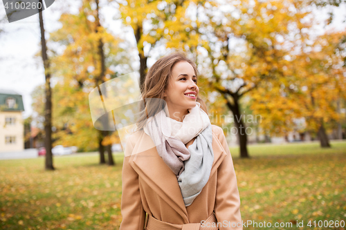 Image of beautiful happy young woman walking in autumn park