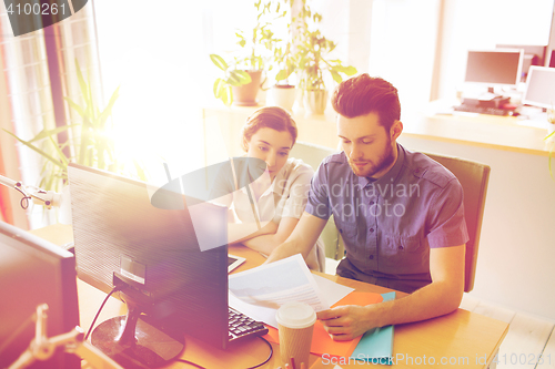 Image of creative team with computer and papers in office