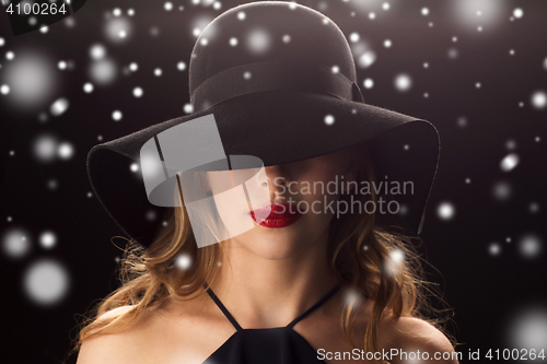 Image of beautiful woman in black hat over snow