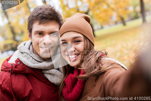 Image of happy young couple taking selfie in autumn park