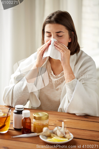 Image of sick woman with medicine blowing nose to wipe