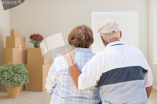 Image of Senior Couple Facing Empty Room with Packed Moving Boxes and Pot