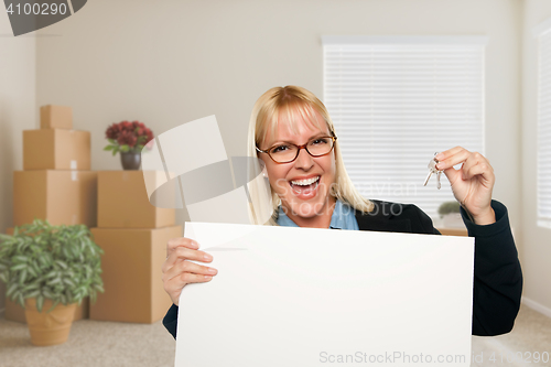 Image of Woman with Blank Sign and House Key in Empty Room with Packed Mo