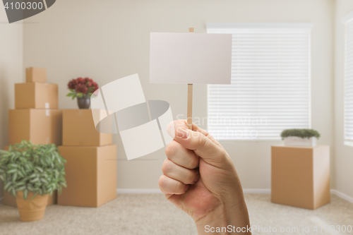 Image of Hand Holding Blank Sign in Empty Room with Packed Moving Boxes